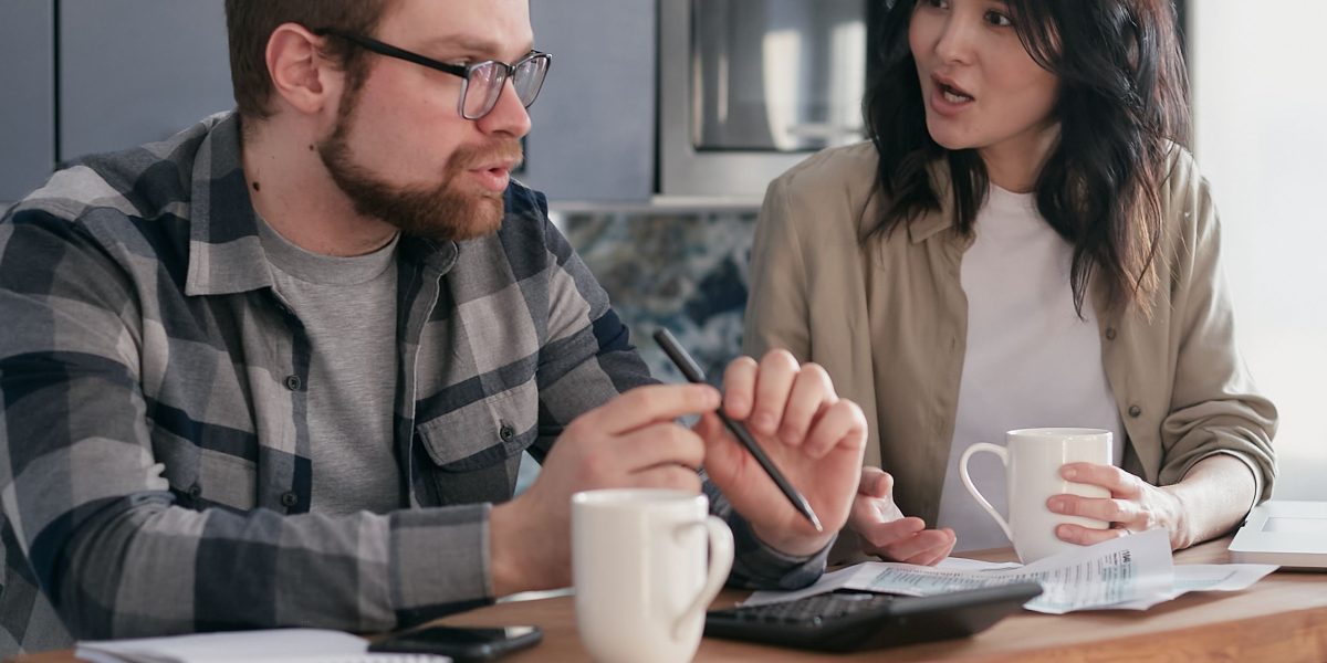 A couple at home, thoughtfully reviewing documents, symbolizing major financial decisions like buying property.