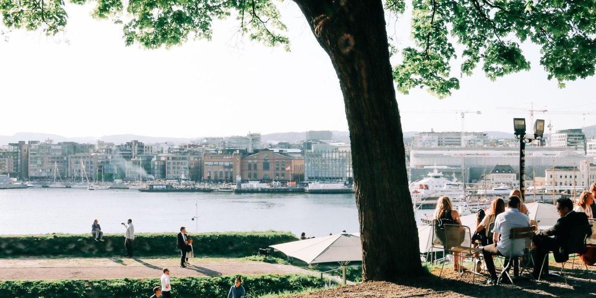 Residents enjoy the vibrant and serene waterfront promenade, with modern architecture in the background.