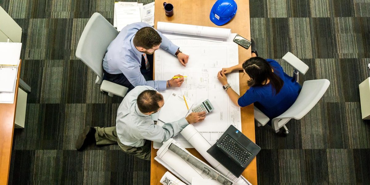 A team collaborating around a whiteboard, analyzing market cycles, infrastructure projects, and demand drivers for real estate investments.